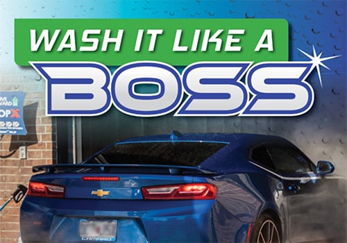 A blue two door sports car entering a car wash stall with text "Wash It Like A Boss" added to the top of the image